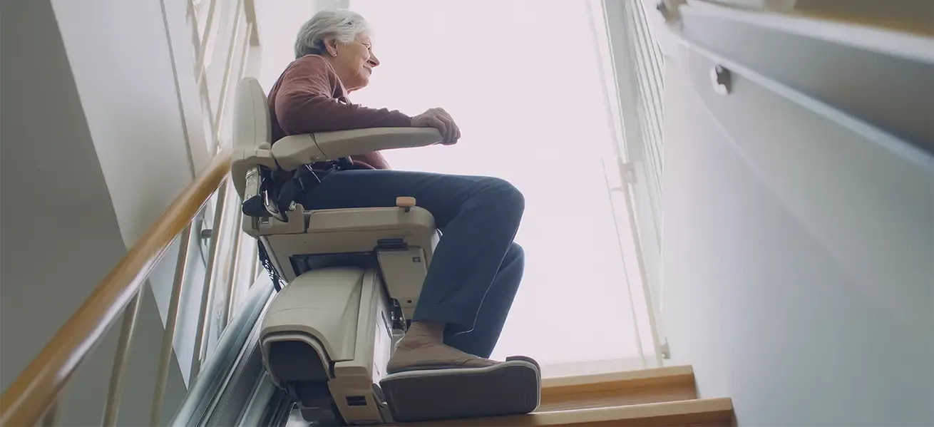 A senior riding a stair lift installed by Home Help Network